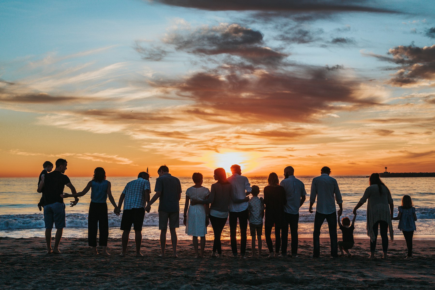 A multi-generation family together on the beach at sunset